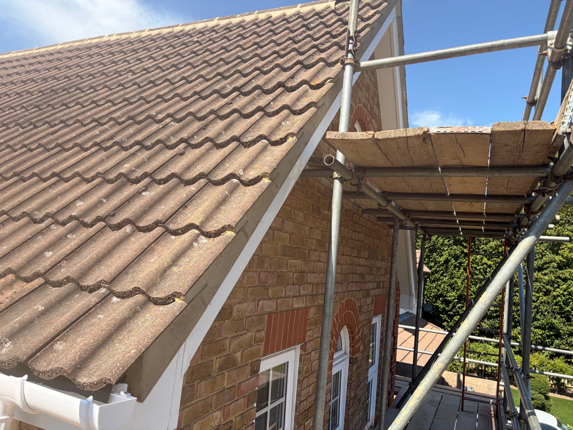 Roof gable end showing new white fascia and fresh mortar bedding to the edge tiles