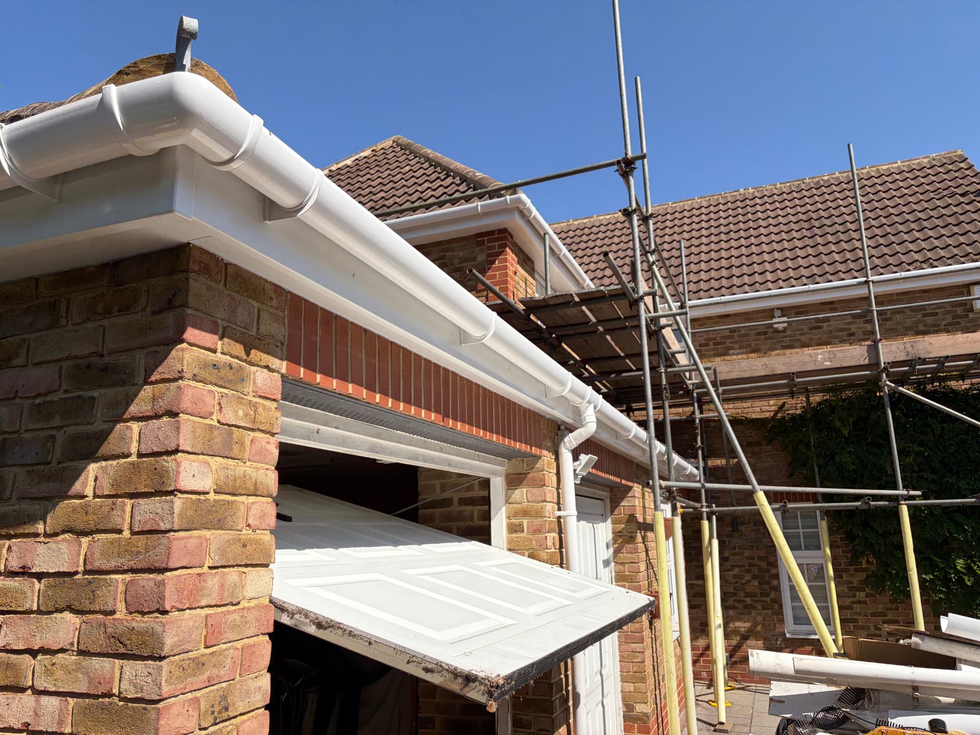 New white fascia, soffit and guttering wrapping the garage corner with scaffold still in place