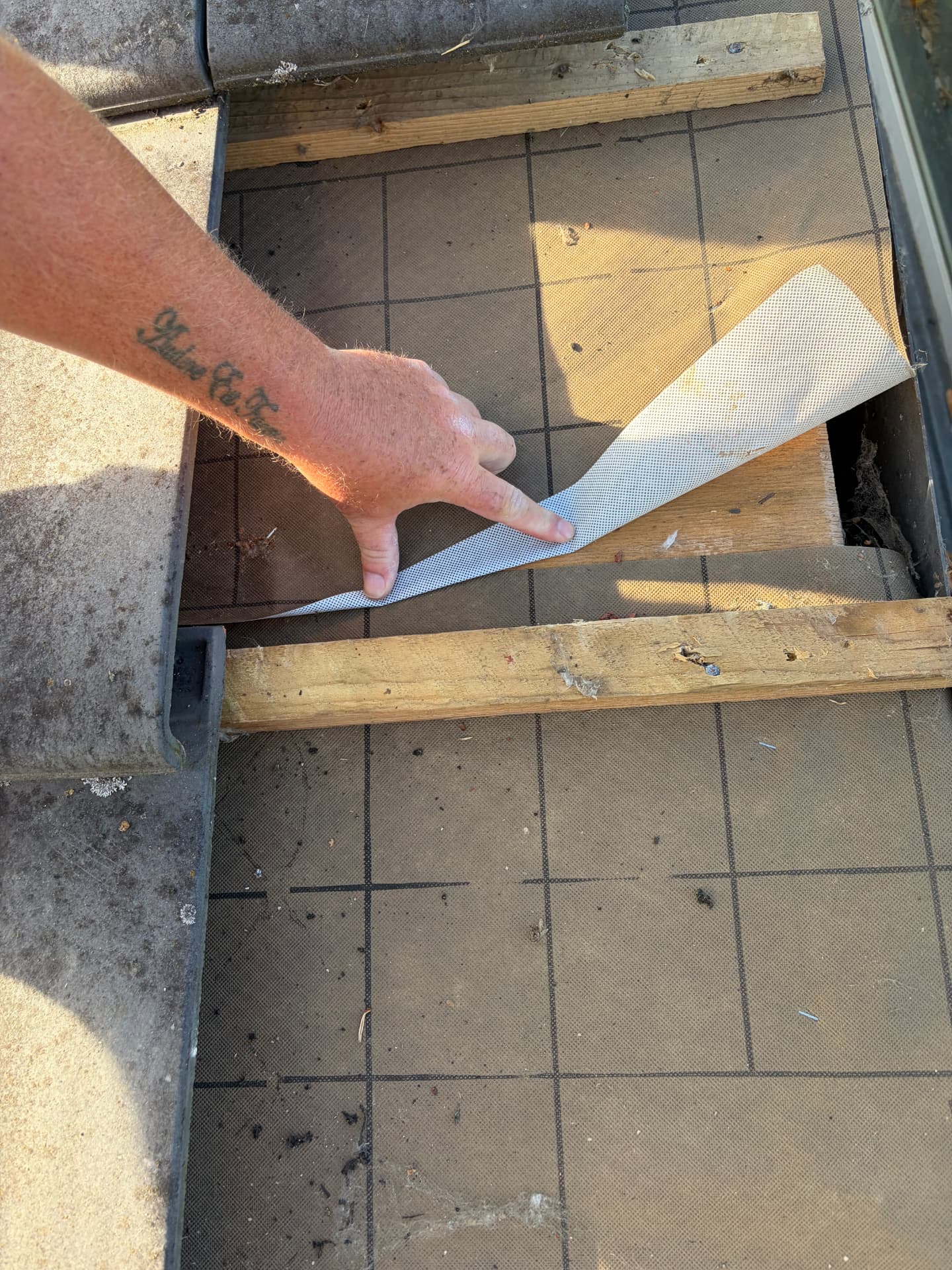Roofer lifting the underlay to show butyl nail sealing tape along the rafter line